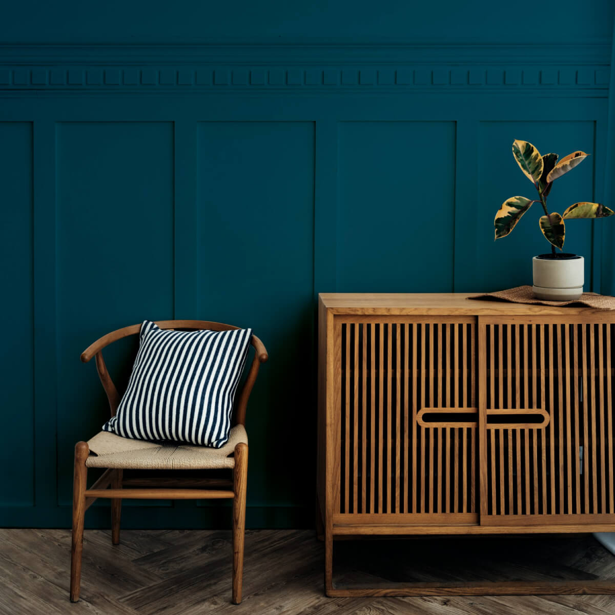 Modern home interior with navy blue walls and sustainable wooden furniture, featuring a striped cushion for a pop of pattern in interior design.