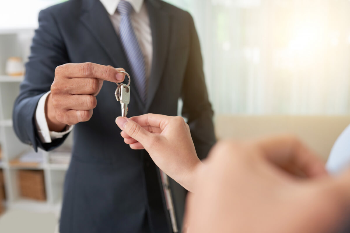 Real estate agent giving house keys to a buyer, a strategic move in today's market to sell your house fast.
