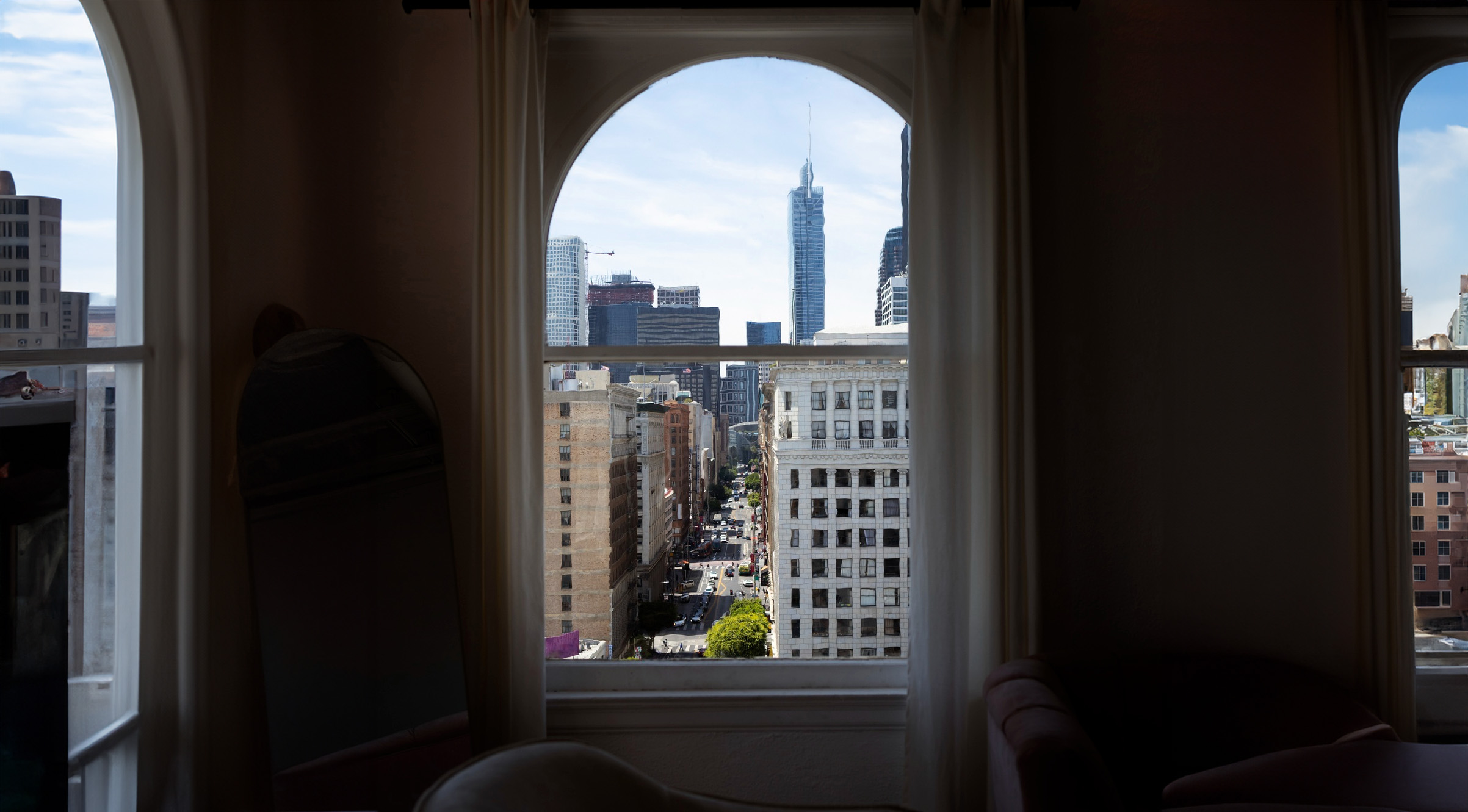 City skyline and urban street view seen through a window, highlighting a high-rise building and downtown area from an interior perspective.